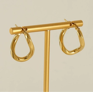 Close-up of golden irregular twisted earrings on a matching metal jewelry stand