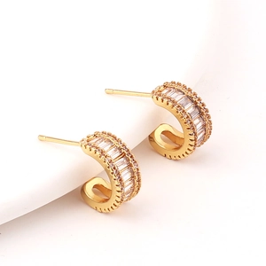 Detail of gold C-shaped hoop earrings with double row micro-pave rectangular gemstones