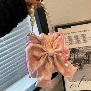 Pink jacquard bucket bag featuring a large bow and elegant pearl handle detail