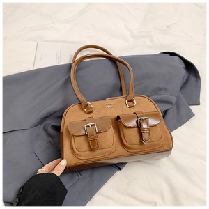 Detail of a brown leather shoulder bag with buckle pockets and silver metal hardware