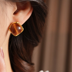 Gros plan sur des boucles d'oreilles vintage avec cadre doré et pierre œil de chat brune