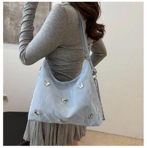 Detail of light blue crossbody bag with silver metal butterflies and chain strap