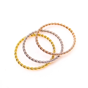 Macro detail of three-tone twisted rope rings in gold, silver, and rose gold finish