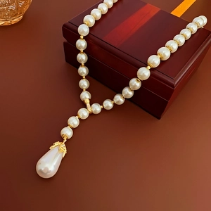 Close-up of teardrop pearl pendant with gold setting on luxury beaded choker necklace