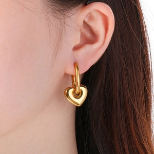 Gros plan d'un modèle portant des boucles d'oreilles cœur creux en acier plaqué or 18K