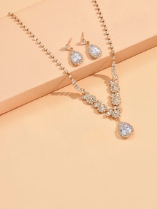 Detailed close-up of sparkling golden teardrop zirconia necklace and earring bridal set