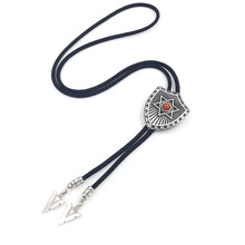 Macro detail of Bolo Tie featuring black braided leather cord and silver shield buckle with red gem