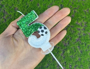 Vue macro de la bougie d'anniversaire chiffre 5 vert pailleté avec décor de football