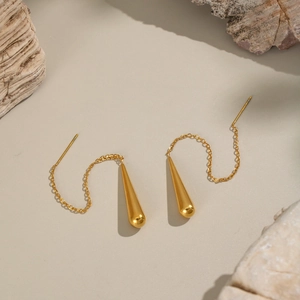 Vue détaillée de boucles d'oreilles pampilles gouttes plaquées or 18K sur fond texturé