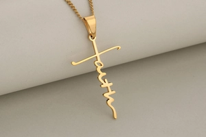 Detailed close-up of golden stainless steel cross pendant featuring Faith inscription