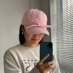 Close-up of pink baseball cap with sweet satin ribbon bow detail on the brim