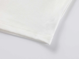 Macro view of white modal knit fabric showing high-quality double-needle stitching on hem