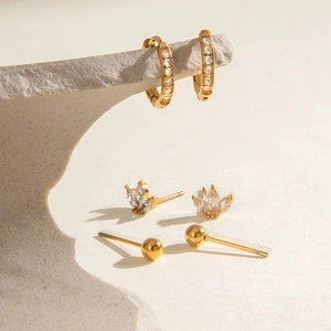 Détail d'un ensemble de trois boucles d'oreilles dorées avec anneaux zircon et puces marquise
