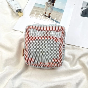 Detail of blue mesh mini cosmetic bag with orange lining on white textured fabric