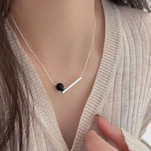 Macro shot of 925 sterling silver necklace with minimalist black onyx bead and metal bar