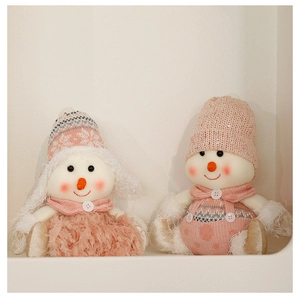 Close-up of plush Christmas snowmen dolls in pink and cream with knit hats and scarves