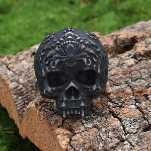Detail of vintage gothic skull ring with intricate silver carvings on natural bark