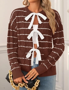 Detail of brown cable knit cardigan with white bow ties and delicate striped patterns