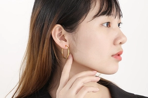 Close-up of a stylish gold stainless steel hoop earring worn by a female model