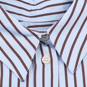 Détail du col d'une chemise en popeline à rayures bleues avec boutons beige et couture fine