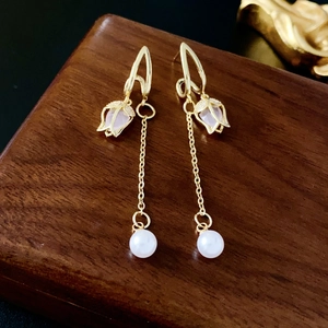 Detail of tulip pendant earrings with pink crystals and round pearls on wood