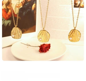 Detailed macro view of gold-tone pendant necklaces with textured surface and small pearl