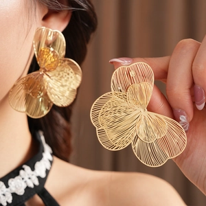 Détail de boucles d'oreilles fleurs ajourées dorées montrant la texture en maille métallique