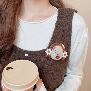 Close-up of handmade woolen felt cartoon girl brooch pinned on a brown knit sweater vest