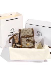 Detailed shot of canvas crossbody bag with bear print, rabbit charm, and gift packaging