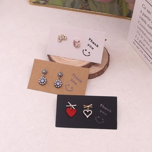 Three pairs of elegant pearl and heart earrings displayed on minimalist thank you cards