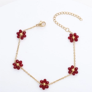 Macro shot of gold stainless steel bracelet with five red crystal flowers and lobster clasp