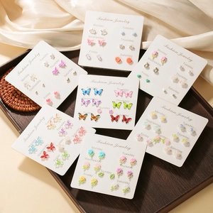 7-day butterfly stud earring set with colorful resin flowers on elegant wood tray