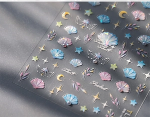 Detail of 3D shell nail stickers with pearls and ocean motifs on grey texture