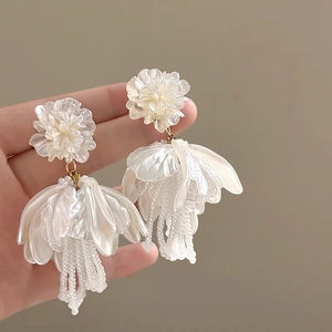 Detail of white flower pearl tassel earrings with pearl bead fringe and golden metal parts