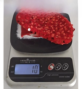 Weight measurement showing a 10g red sequin Christmas stocking with white plush trim