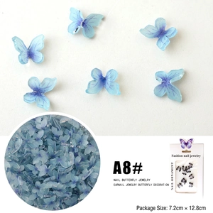 Detailed view of blue 3D resin butterfly nail charms with retail packaging and size info