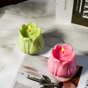 Détail de bougies tulipes en rose et vert allumées sur un comptoir en marbre chic