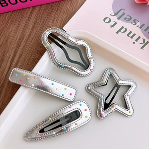 Detail of four silver leather hair clips with colorful dots and metallic BB clip base