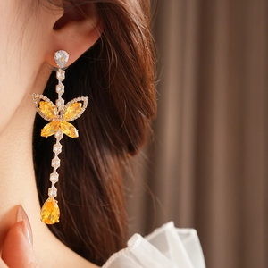 Detail of gold flower and teardrop earrings with yellow zircons on a model