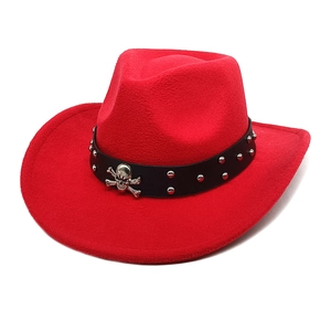 Détail d'un chapeau de cowboy rouge avec bandeau en cuir noir, rivets et têtes de mort