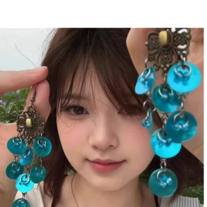 Close-up of vintage long fringe earrings with peacock blue shell sequins on bronze metal