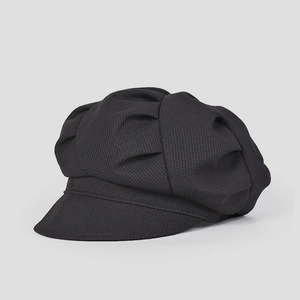 Vue détaillée du tissu en maille texturé et des plis de cette casquette gavroche noire