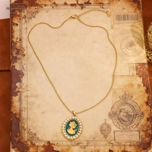 Detail of vintage gold necklace with green enamel portrait pendant and pearl border