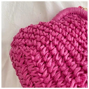 Detailed macro view of the fuchsia straw woven texture and artisanal chain on the shoulder bag