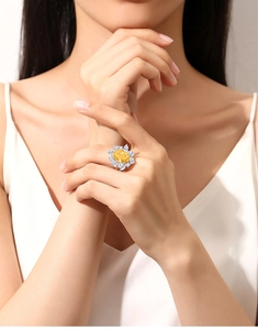 Detailed view of sunflower ring with yellow oval center stone on a hand