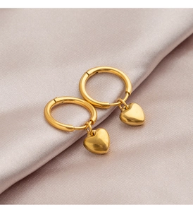 Macro shot of gold heart dangle earrings on smooth purple silk fabric background