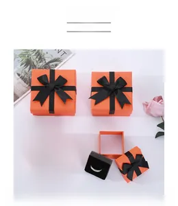 Square orange jewelry box with black ribbon bow and ring on black sponge foam insert