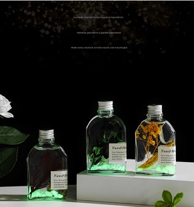 Détail de flacons d'arôme en verre avec fleurs éternelles et base lumineuse à LED douce