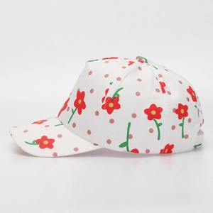 Close-up of white cotton kid's baseball cap with red floral patterns and pink polka dots