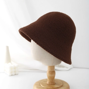 Close-up of a dark brown plush bucket hat on a mannequin head with minimalist background
